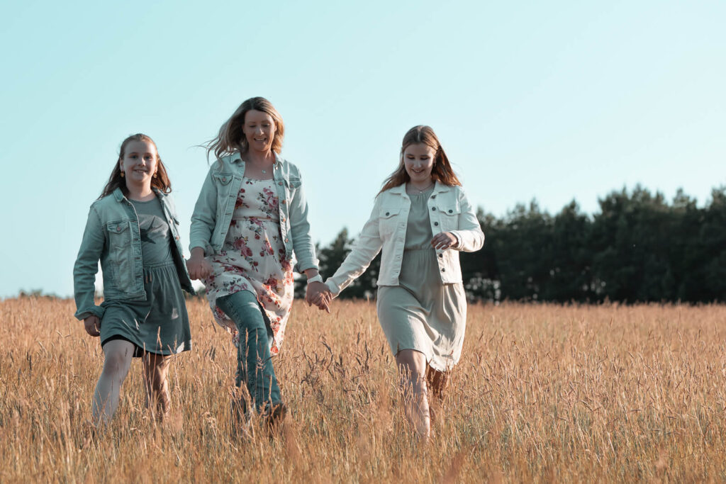 Beschwingter Spaziergang auf einer Sommerwiese beim Familienshooting