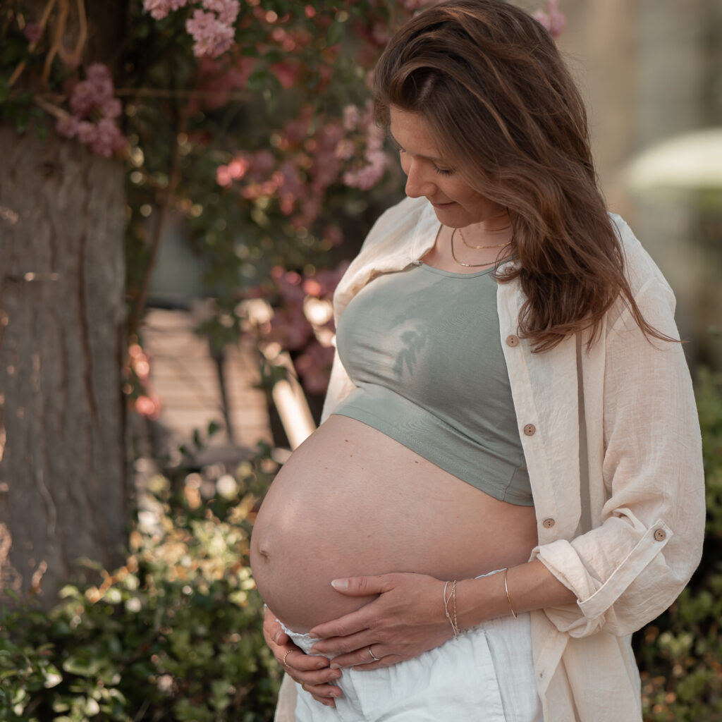 Babybauchshooting in Hankensbüttel - verträumter Blick einer Frau auf ihren Babybauch - im Rosengarten