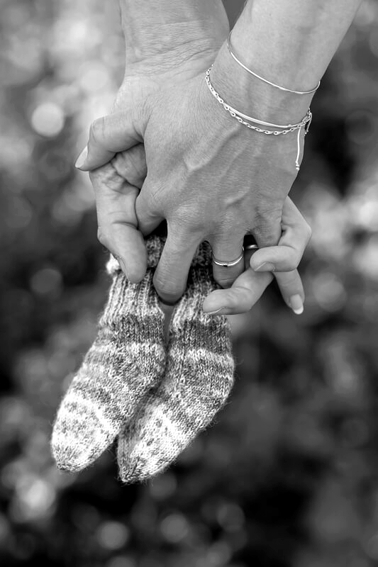 Babybauch-Shooting Hankensbüttel - Hände der Eltern verschränkt mit Babysöckchen