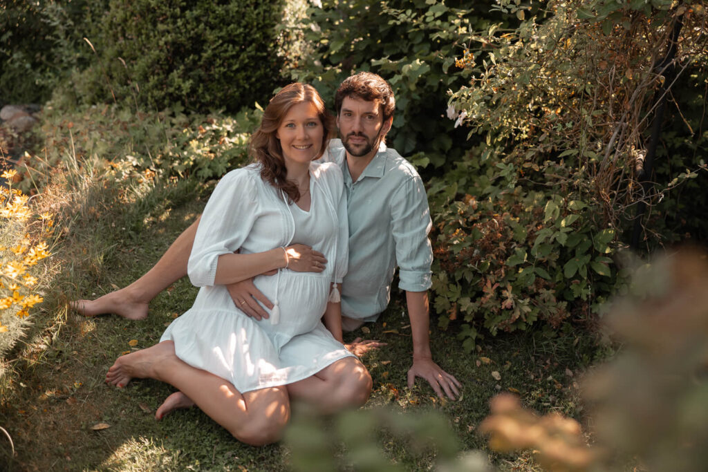 Babybauchshooting-Hankensbüttel - junges Paar glücklich und erwartungsvoll im Gras sitzend