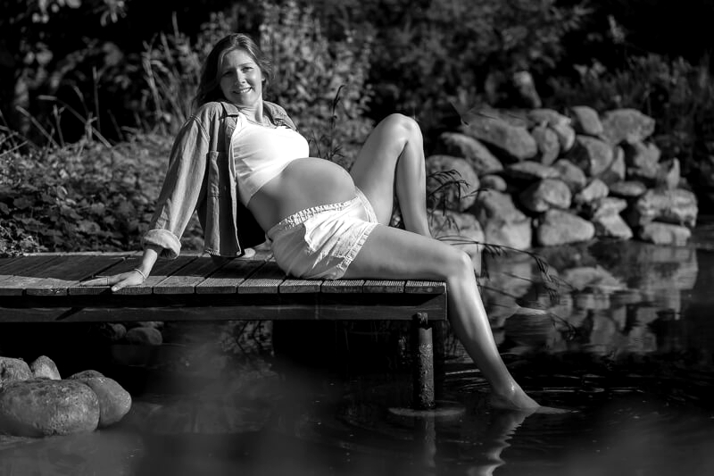 Sommerliches Babybauchshooting Hankensbüttel - Frau mit Babybauch fröhlich auf einem Steg am Wasser
