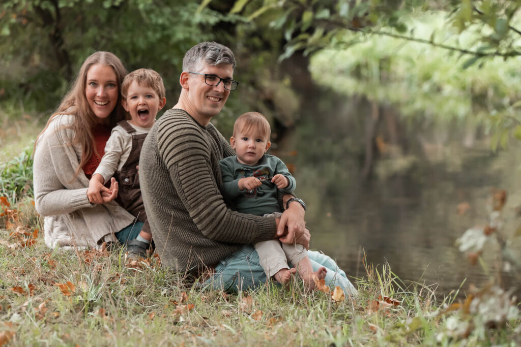Fröhliche Familienfotos in Hankensbüttel - vierköpfige Familie sitzt am Bachufer