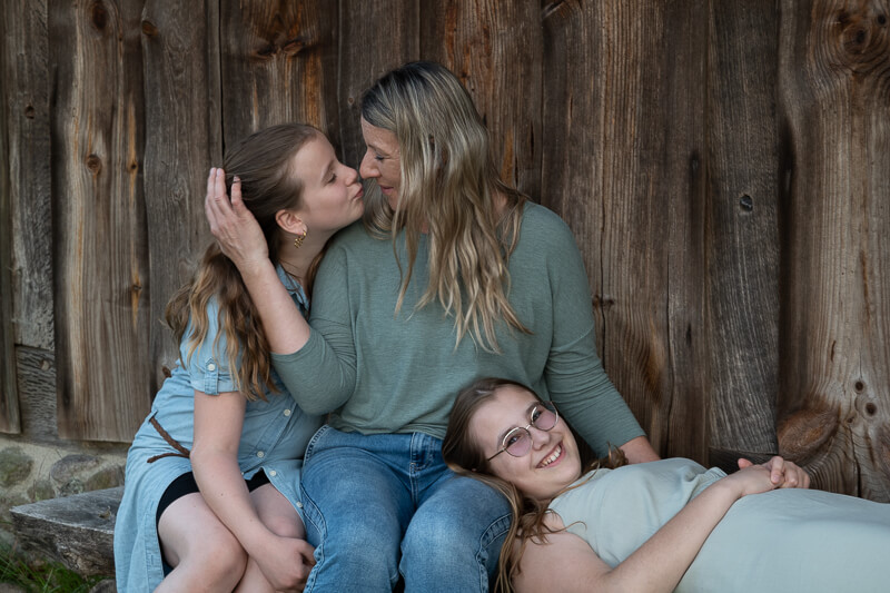 Familienfotos in vertrauter und sicherer Atmosphäre - kleine Familie vor einer Holzwand
