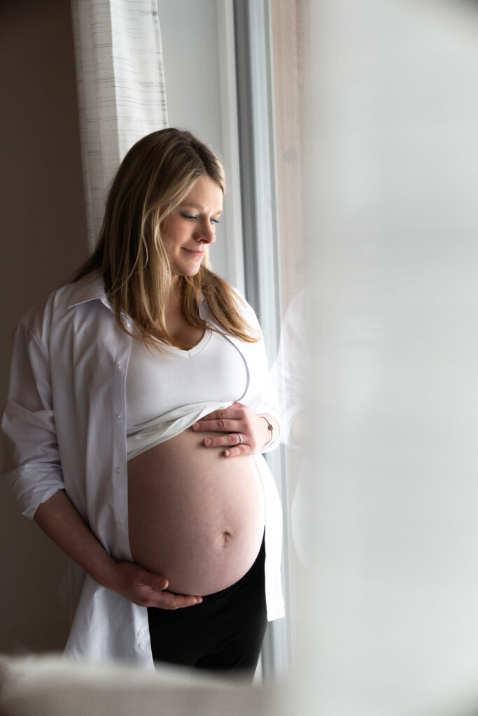 Babybauchfoto - Homestory im Winter am Fenster