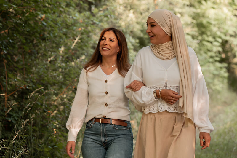 Freundinnen-Shooting in Hankensbüttel am See - Die beiden Freundinnen spazieren untergehakt durch den bewaldeten Uferbereich