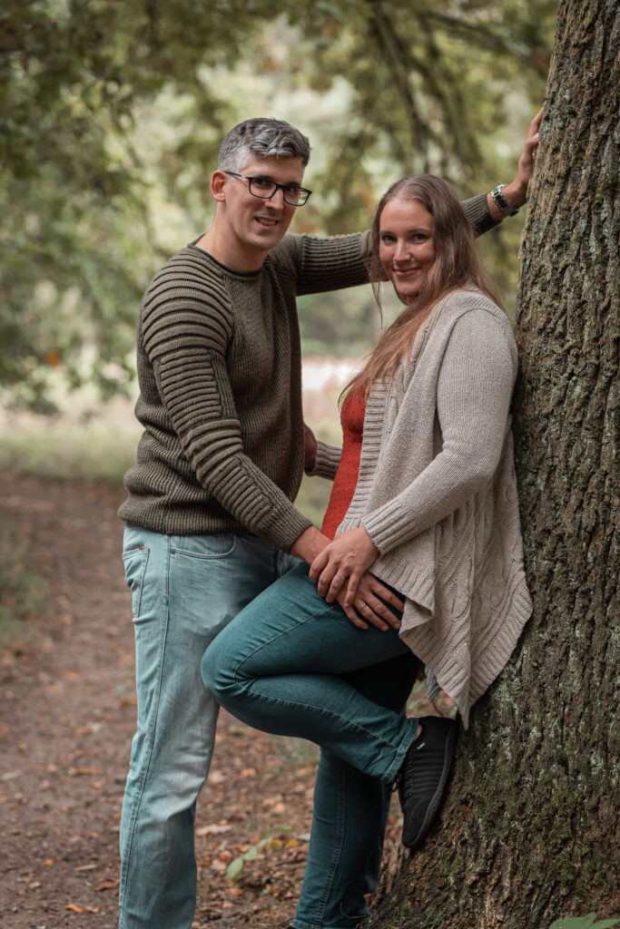 Paar beim Shooting im Wald an einen Baumgelehnt