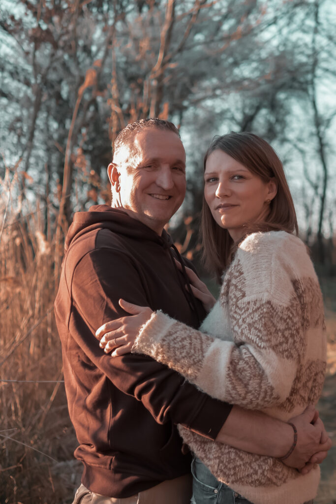 Paarfotografie - beide Arm in Arm vertraut und geborgen mit Blick in die Kamera