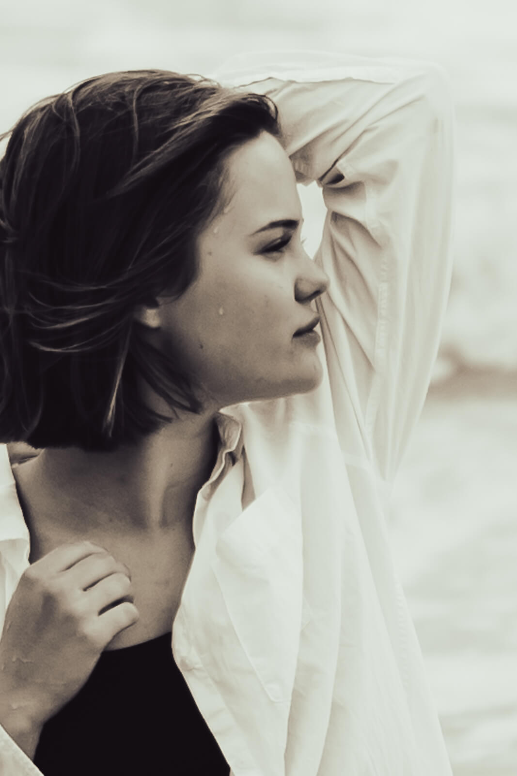 Portraitfoto einer selbstbewussten jungen Frau mit Blick in die Ferne und Wassertropfen im Gesicht