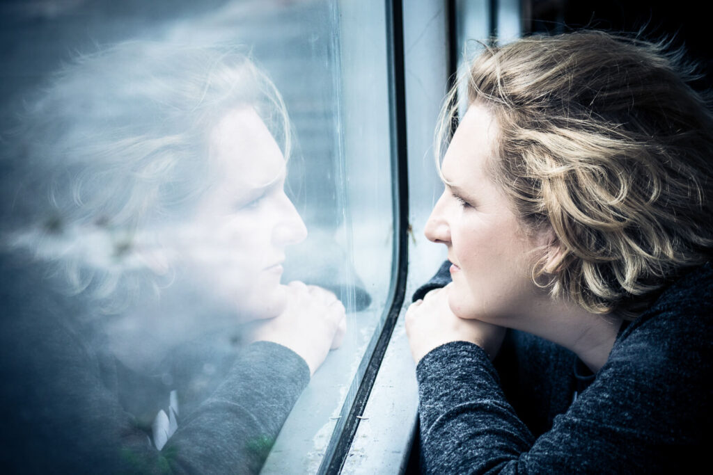 Portraitfoto Hankensbüttel - Frau spiegelt sich im Fenster eines Busses