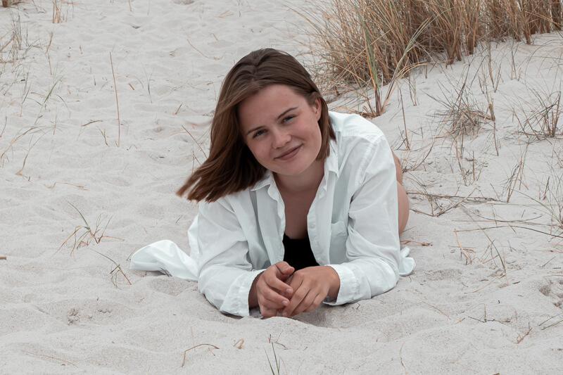Foto einer Frau aus einem Portraitshooting. Sie liegt in einer Dünenlandschaft