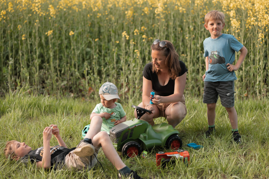 Foto von einer spielenden Familie im Gras am Rapsfeld