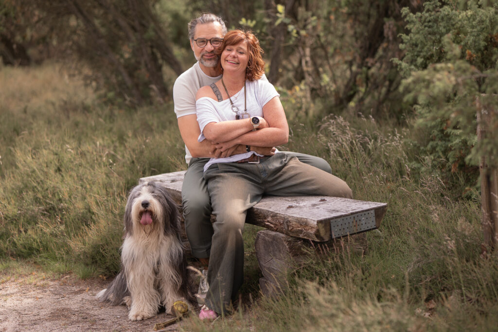 Paar Arm in Arm auf einer Bank in der Heide mit Hund